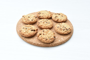 Oatmeal cookies and chocolate chips on light background