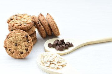 Oatmeal cookies and chocolate chips on light background