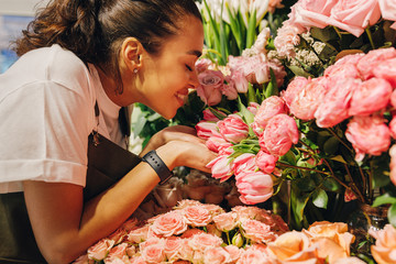 Side view of a young woman smelling the flowers with closed eyes - obrazy, fototapety, plakaty