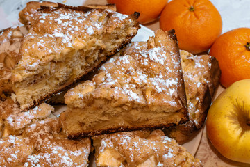 Slices of apple pie with fruits lying nearby. Apple pie, apple and tangerines on the table