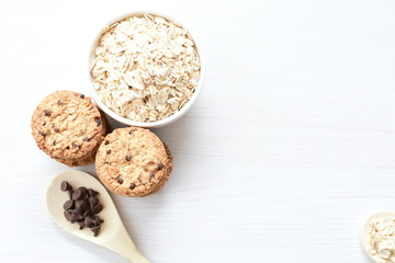 Oatmeal cookies and chocolate chips on light background