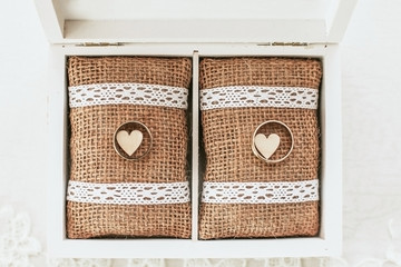 Gold wedding rings. Wood box rustic linen fabric. Heat shape love symbol.