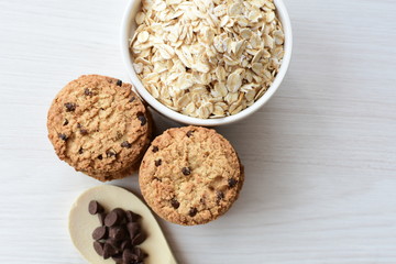 Oatmeal cookies and chocolate chips on light background