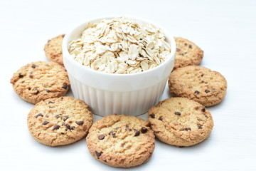 Oatmeal cookies and chocolate chips on light background
