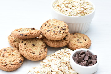 Oatmeal cookies and chocolate chips on light background