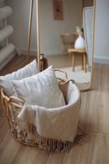 Fototapeta na wymiar gray plaid with a pattern and gray pillows in a wooden basket in the interior