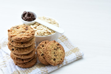 Oatmeal cookies and chocolate chips on light background