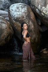 Joven morena de pelo de pie posando junto a las rocas en las montañas mojada dentro del agua...