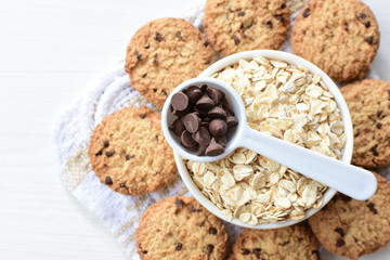 Oatmeal cookies and chocolate chips on light background