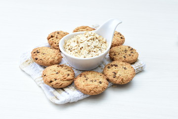 Oatmeal cookies and chocolate chips on light background