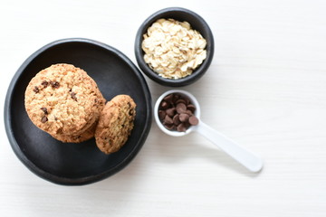 Oatmeal cookies and chocolate chips on light background