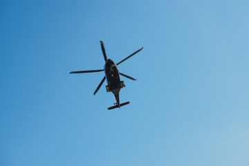 Modern helicopter flying in the blue sky.Flying transport helicopter.The aircraft, the black helicopter at competitions makes flight at low height.