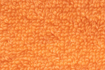 Orange fabric texture. Close-up of a orange fluffy terry bath towel or textile backround. Macro photograph. Beautiful bright backdrop.