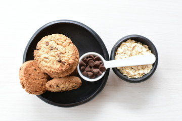 Oatmeal cookies and chocolate chips on light background