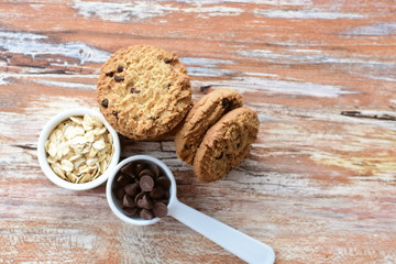 Oatmeal cookies and chocolate chips on light background