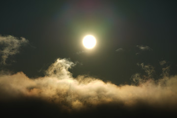 The sun shining over the clouds in the sky.