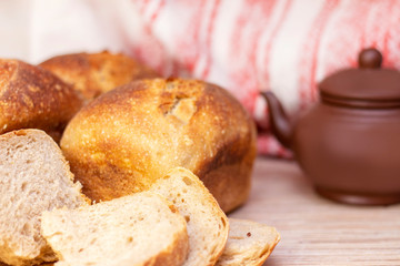 Traditional fresh flavored bread on the table. Food concept. In the background is tea in a teapot