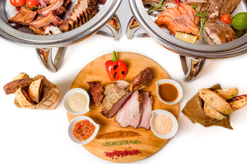 Assorted meat with vegetables and sauce on a white background