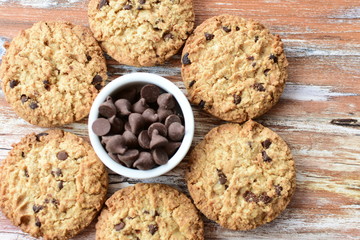 Oatmeal cookies and chocolate chips on light background