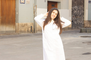 Portrait of relaxed caucasian young woman model touching his head with both hands, having time for rest, looks quiet and peaceful. Slender charismatic man poses. Doctor, nurse, in the city, in white c