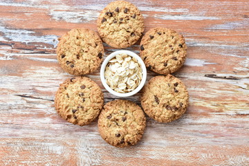 Oatmeal cookies and chocolate chips on light background