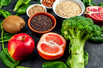 Selection of healthy food:  fruits, seeds, cereals, superfoods, vegetables, leafy vegetables on a stone background. Healthy food for humans.