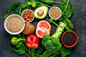 Selection of healthy food:  fruits, seeds, cereals, superfoods, vegetables, leafy vegetables on a stone background. Healthy food for humans.