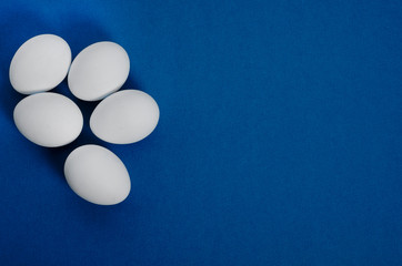 White easter eggs on a classic blue background with copy space. View from above. Flat lay.