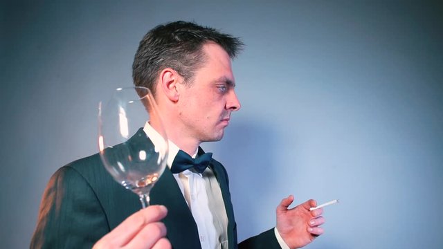 A confused guest in a tuxedo with a broken glass and a cigarette is looking for a waiter. Concept unpleasant moment in a restaurant.