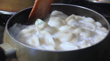 meat dumplings are cooked in hot water in a ladle