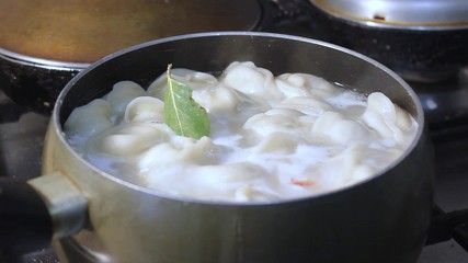 meat dumplings are cooked in hot water in a ladle