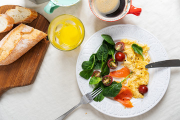 Close view of a plate with an omelet with salmon and spinach on white textile table background. healthy breakfast with fresh juice and coffee.