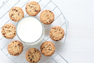 Oatmeal cookies and chocolate chips accompanied by glass of milk