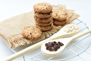 Oatmeal cookies and chocolate chips on light background