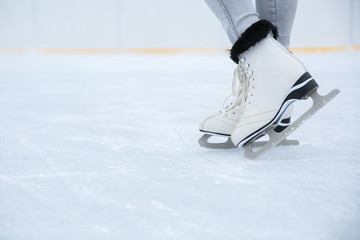 white ice skates is on woman's legs on the rink close up