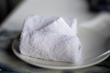 White wet towel for hygenic hand cleaning served on a plate in a restaurant in Bali
