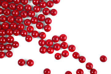 Large red beads are scattered on a white isolated background