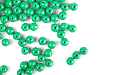 Large green beads are scattered on a white isolated background