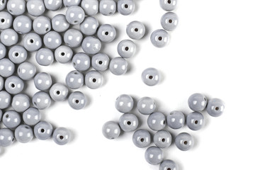 Large grey beads are scattered on a white isolated background