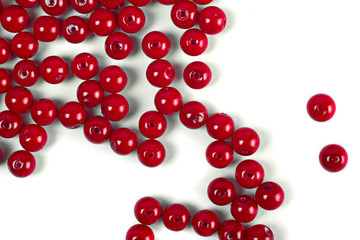 Large red beads are scattered on a white isolated background