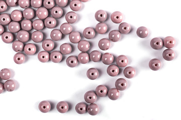 Large lilac colored beads are scattered on a white isolated background