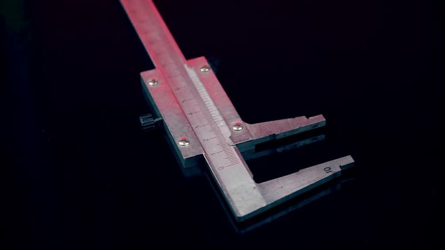 A caliper is rotating isolated on a black background. Precise measurements in production. Measuring tool in metal processing.