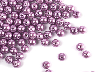 Large lilac colored beads are scattered on a white isolated background