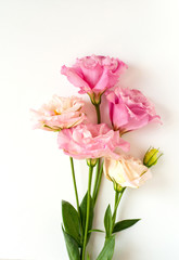 Beautiful pink and white eustoma flowers (lisianthus) in full bloom with green leaves. Bouquet of flowers on a white background.