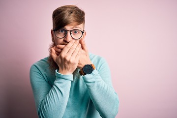 Handsome Irish redhead man with beard wearing glasses over pink isolated background shocked covering mouth with hands for mistake. Secret concept.