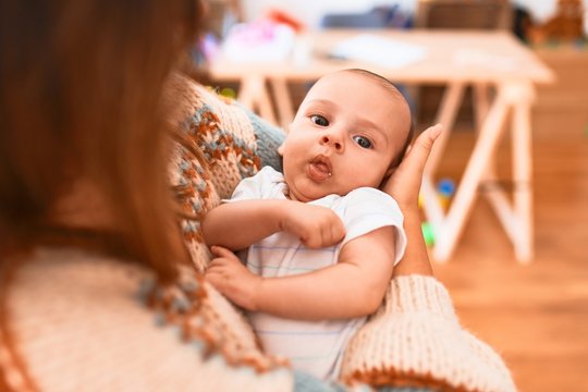 Young beautiful woman and her baby standing at home. Mother holding and hugging newborn