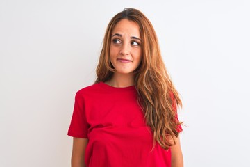 Fototapeta premium Young redhead woman wearing red casual t-shirt stading over white isolated background smiling looking to the side and staring away thinking.
