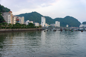 Fototapeta premium Cat Ba island, Vietnam Oct 17, 2019. fishing small boats in the bay. View of the main street with the hotels of Cat Ba
