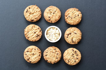 Oatmeal cookies and chocolate chips on black background