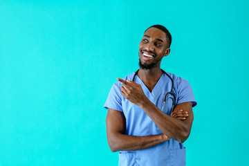 Portrait of a smiling male doctor or nurse looking to side at copy space and pointing with finger
